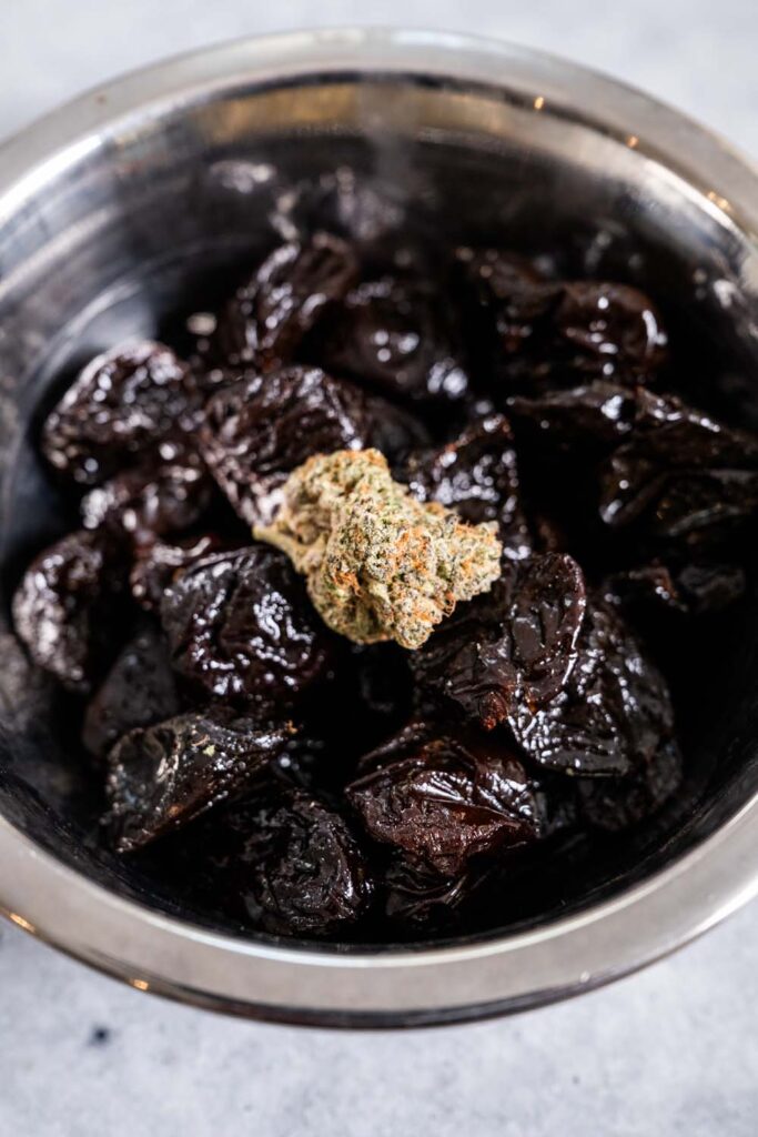 A bowl of prunes with a cannabis bud on top.
