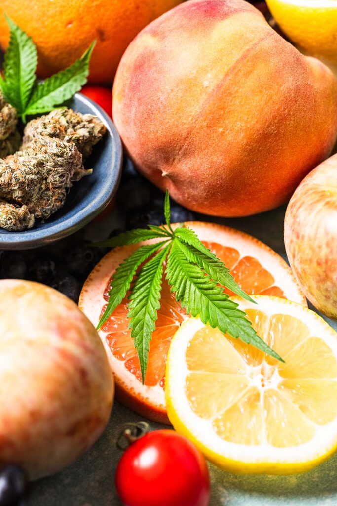 An image of sliced citrus and whole stone fruit with cannabis.